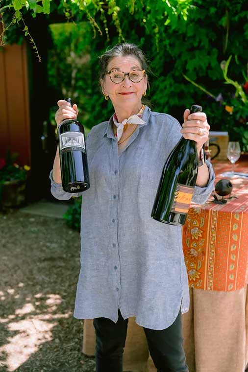 Tres Sabores winemaker Julie Johnson holding up a bottle of wine in each hand