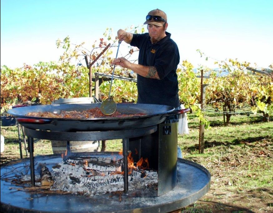 Cooking Paella in large open fire next to vineyard